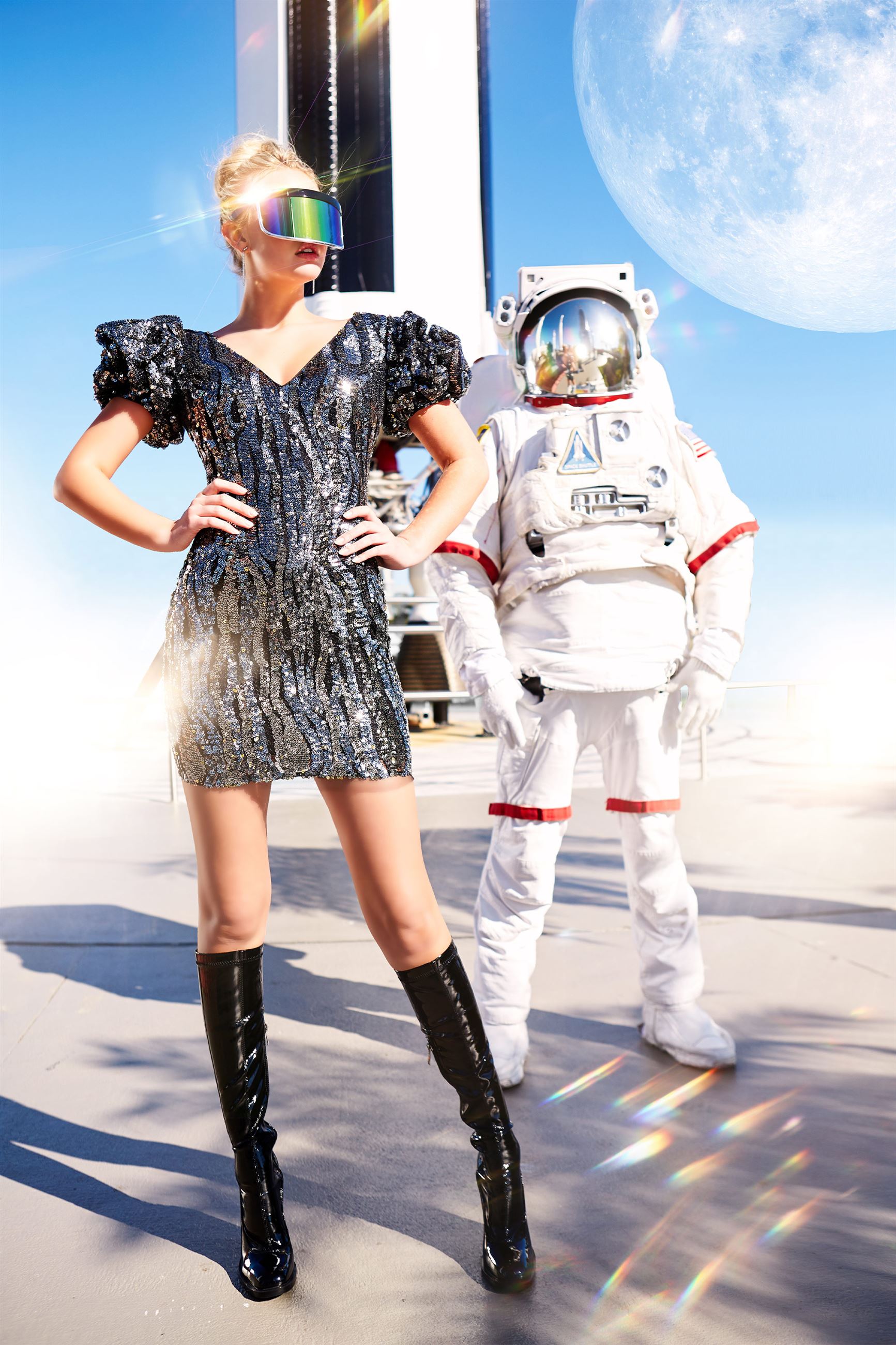 Blonde model in short black and silver dress next to astronaut