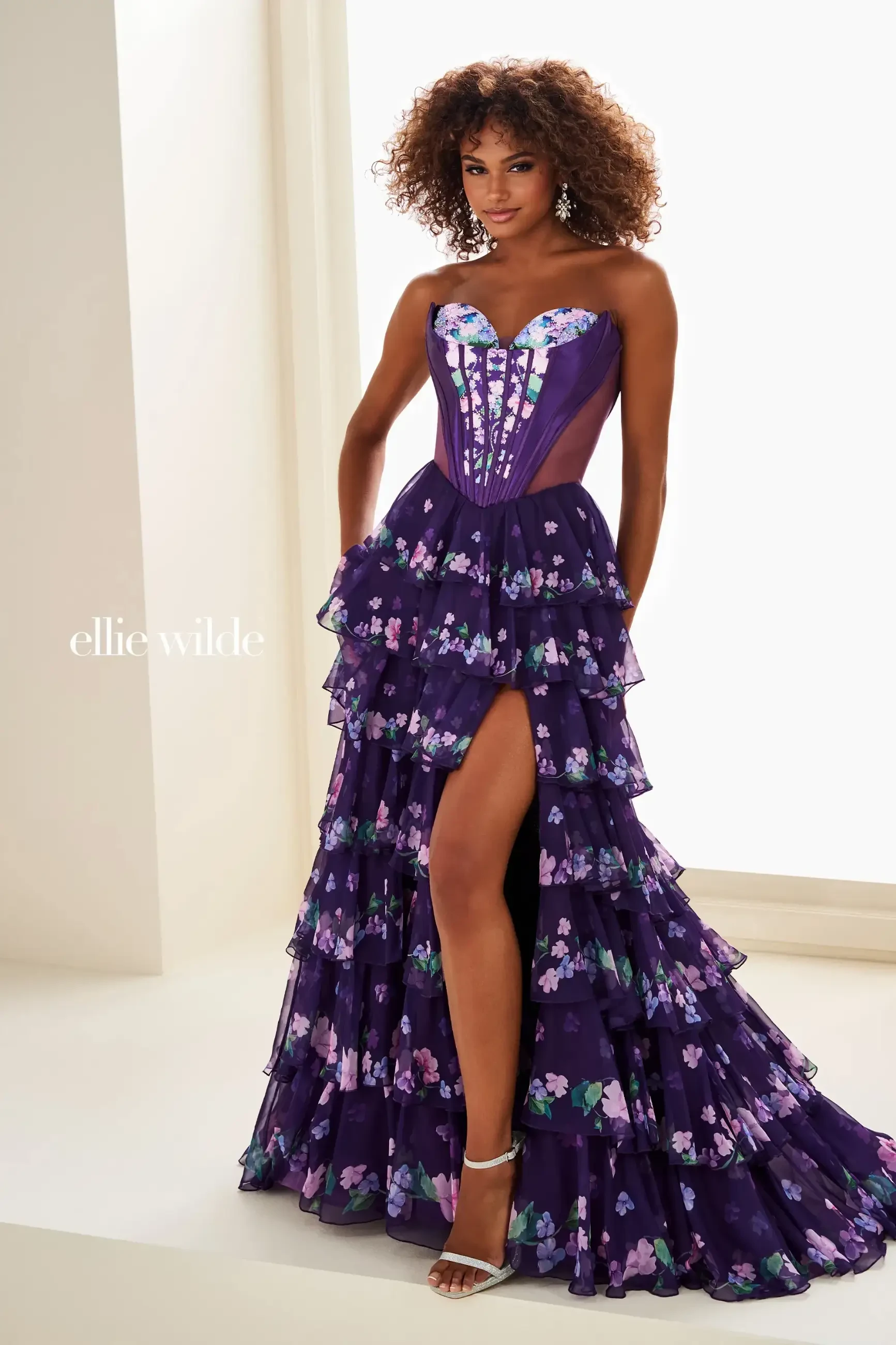 Model is wearing an A-line prom gown with a corset bodice and basque waist
