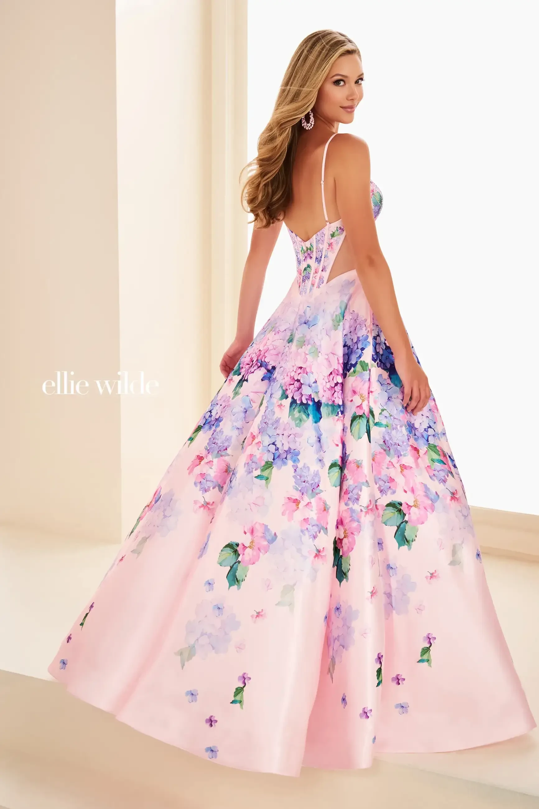 Model is wearing a floral ball gown with a corset bodice