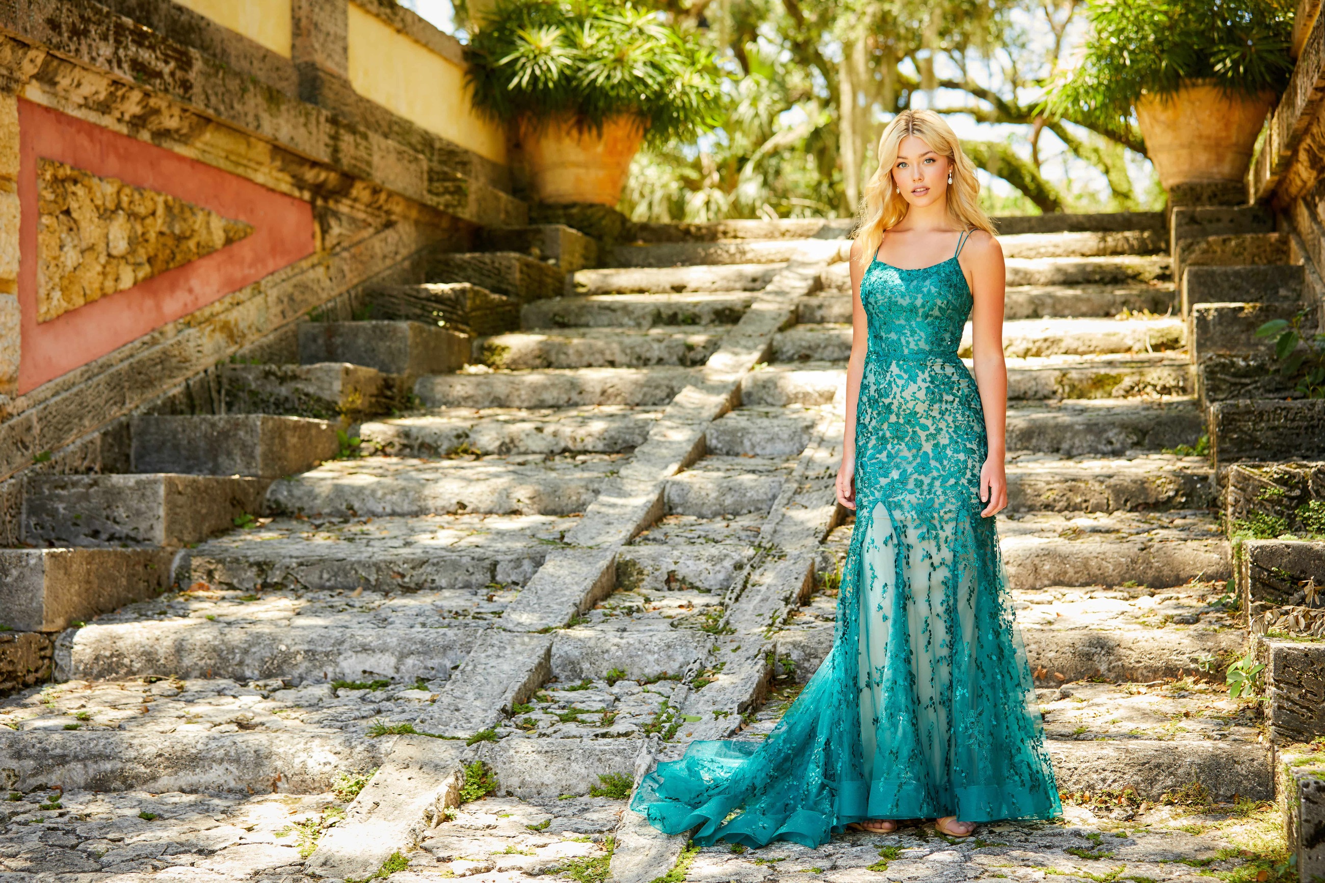 Blonde girl wearing long green dress in front of ancient steps. Front