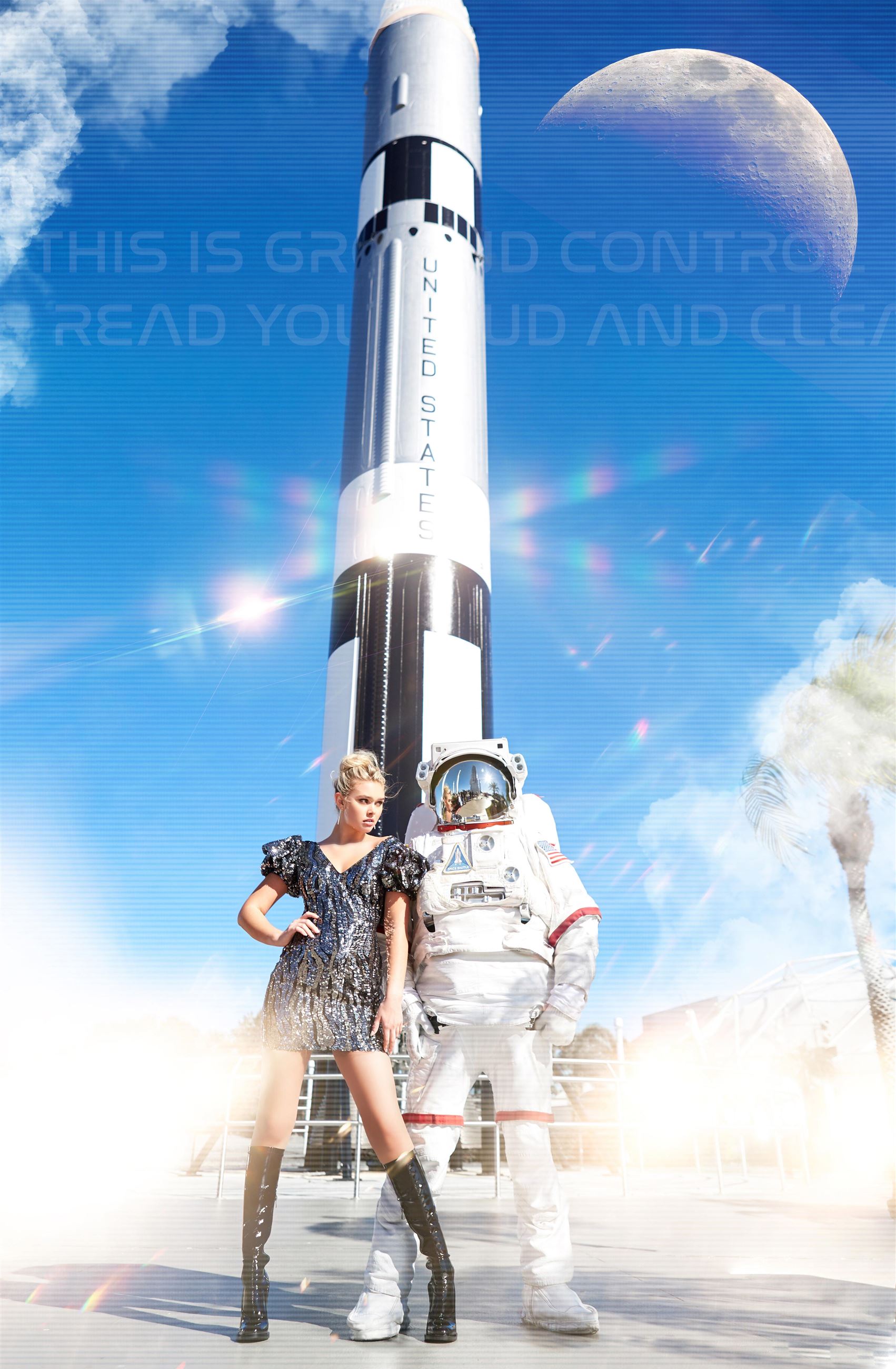 Girl standing in front of astronaut and rocket, wearing silver sequin dress