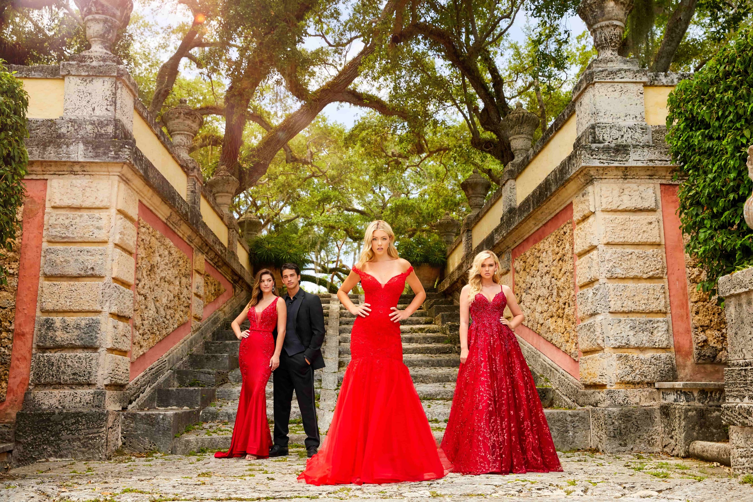 3 girls wearing red dresses of different shades and shapes